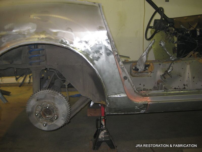 A car is being repaired in a garage with a wheel on a jack.