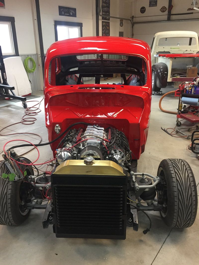 A red car with a v8 engine is being built in a garage.