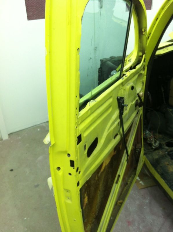 A yellow car with the door open in a garage
