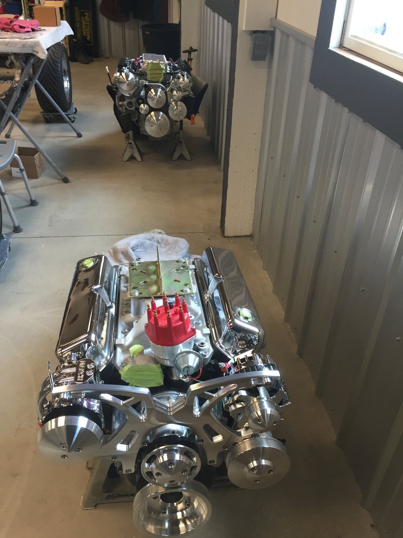 A chrome engine is sitting on a table in a garage.