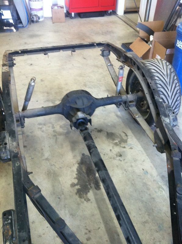 A rear end of a car is sitting on the ground in a garage