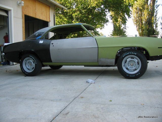 A green and black car is parked in front of a garage