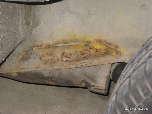 A close up of a rusty piece of metal next to a tire.