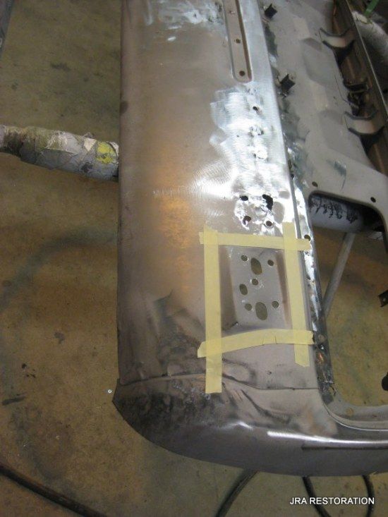 A piece of metal is taped to a table and says jra restoration on the bottom