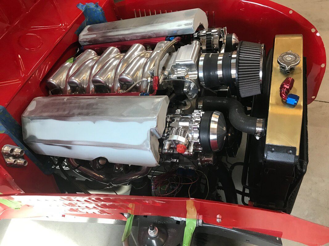 The engine of a red car is being worked on.
