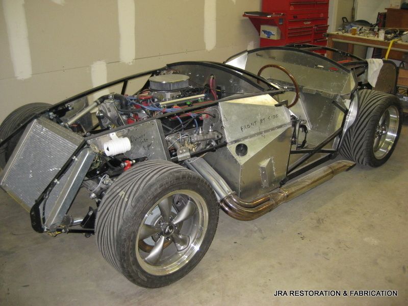 A car with the engine removed is sitting in a garage.