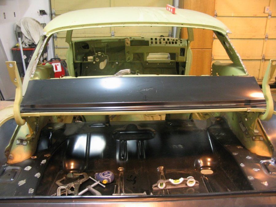 A car is being built in a garage with a red fire extinguisher in the background