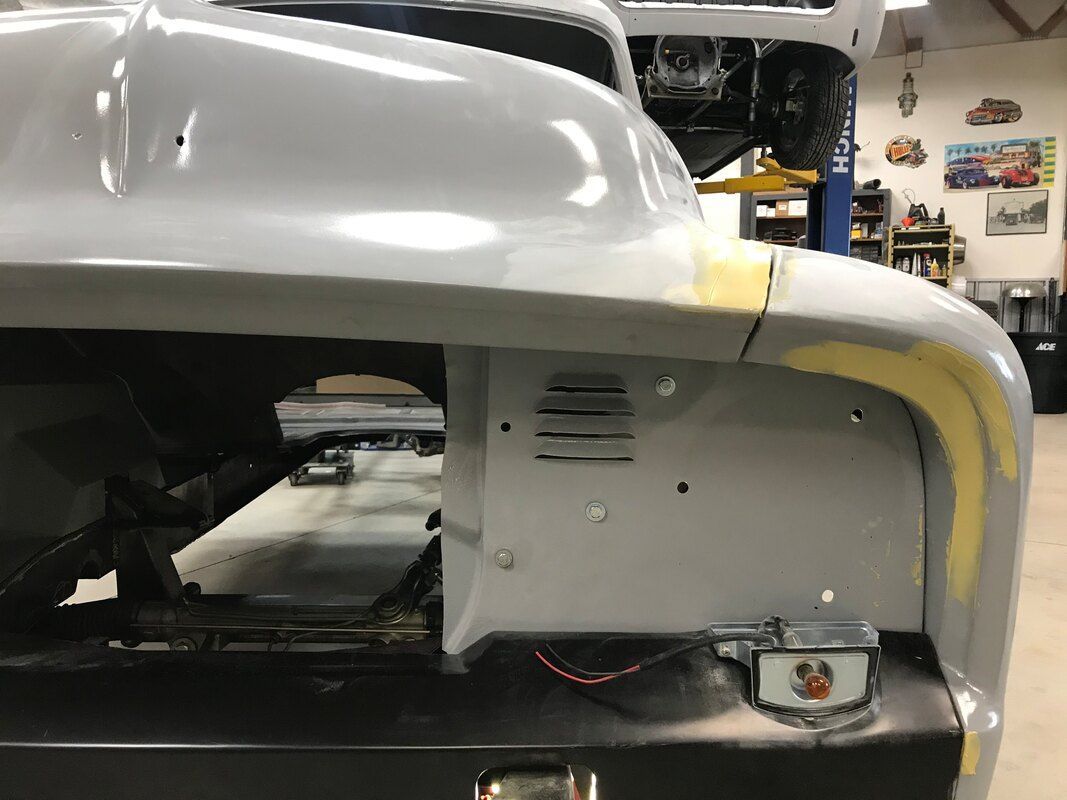 A white car is being built in a garage.