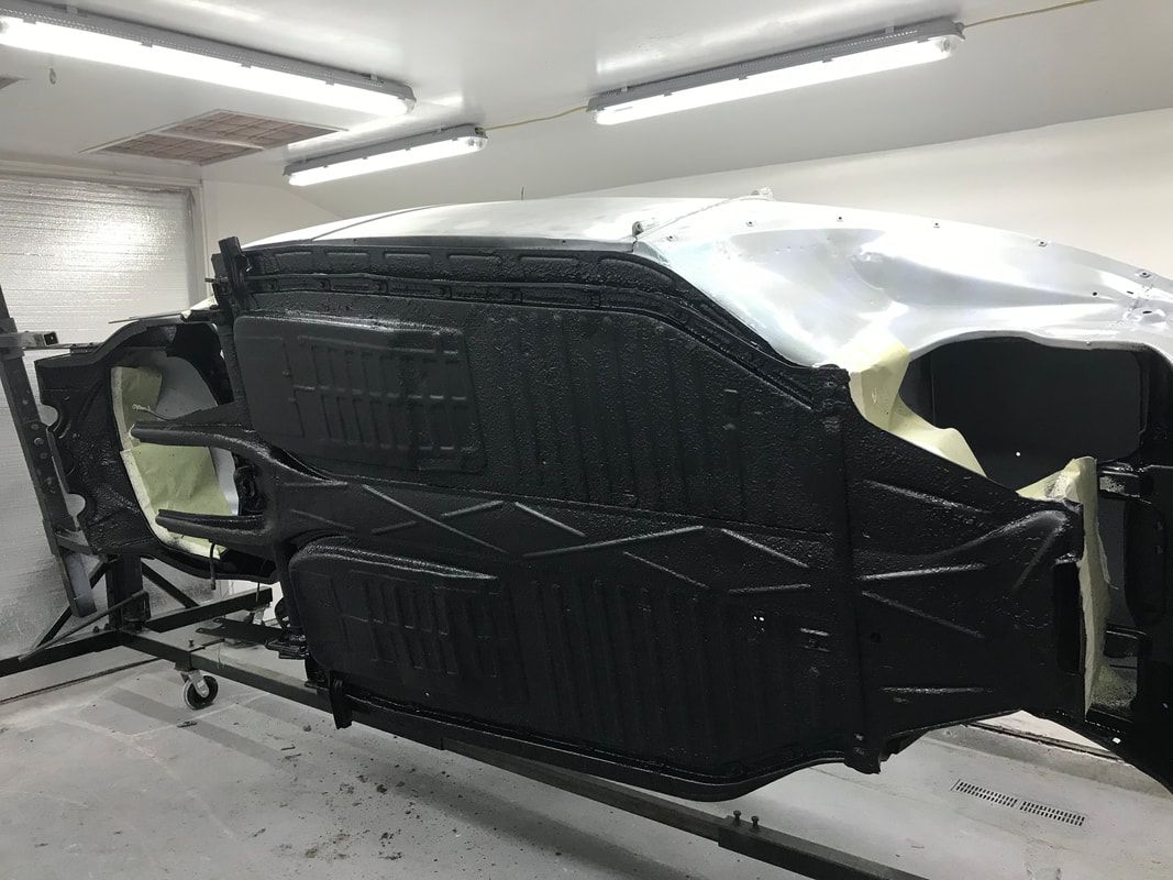 A car is being painted in a garage.