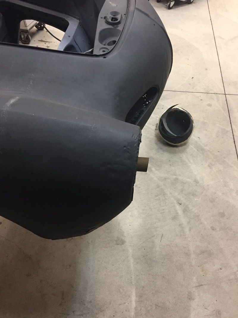 A black car is sitting on a concrete floor next to a black object.