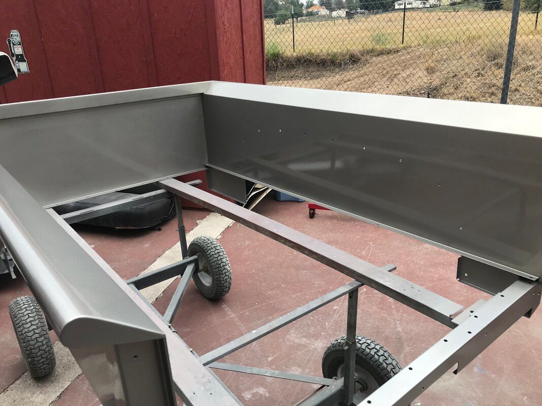 A metal frame with wheels is sitting on the ground in front of a red shed.