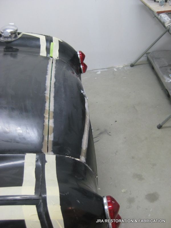 A black car with white stripes is taped to the floor