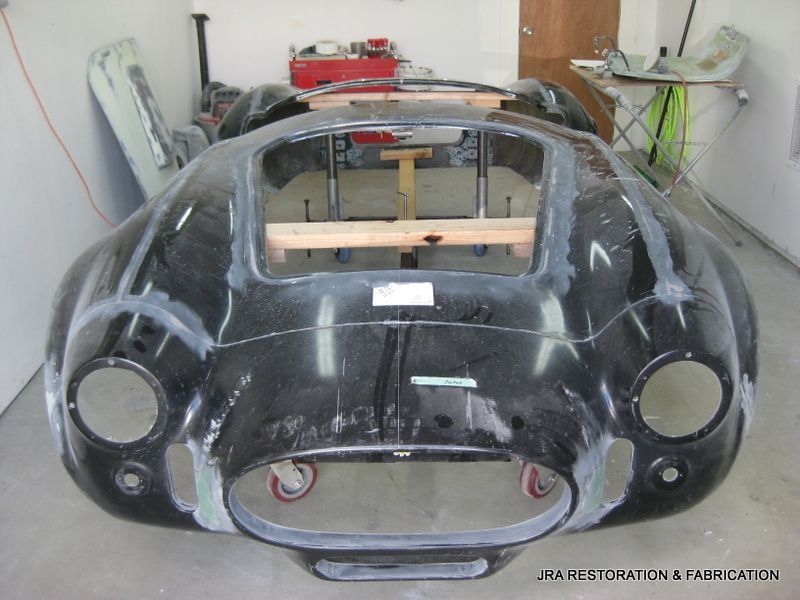 A black car is being restored in a garage