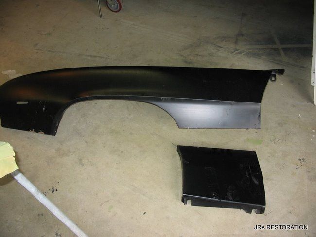 A black car fender is laying on the ground