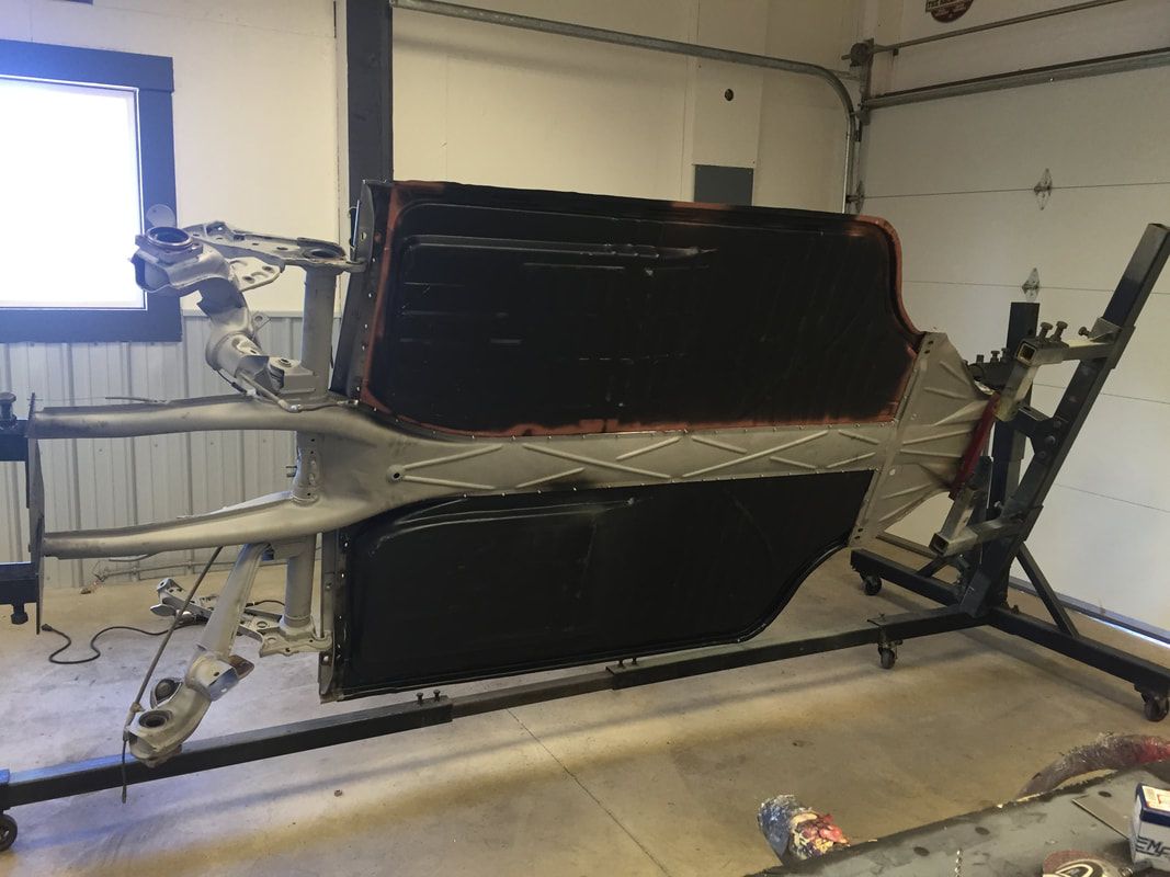 A car frame is sitting on a stand in a garage.