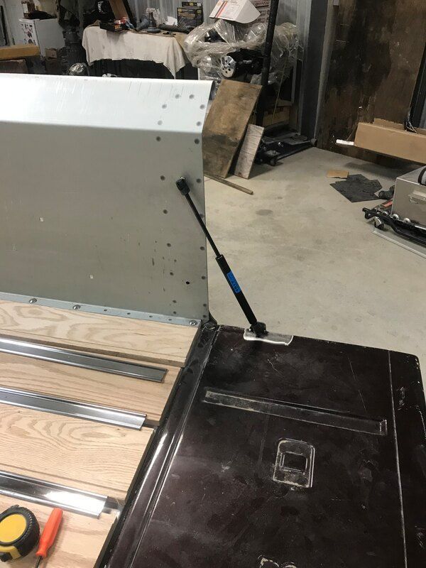 A person is working on a piece of furniture in a garage.