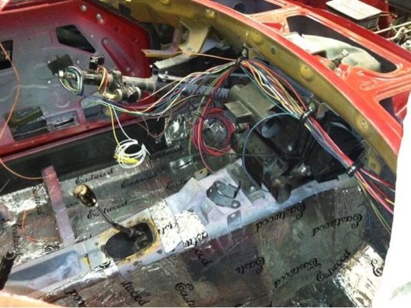 The inside of a red car with a lot of wires coming out of it