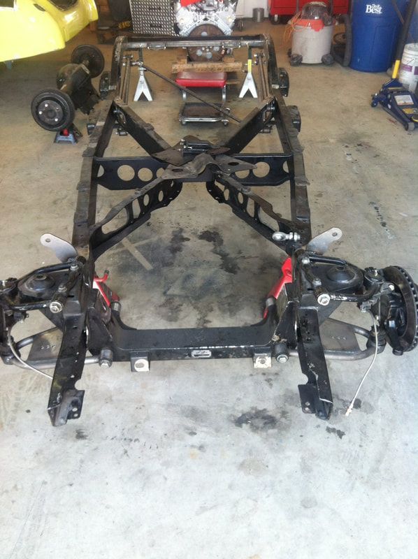 A car frame is sitting on the ground in a garage