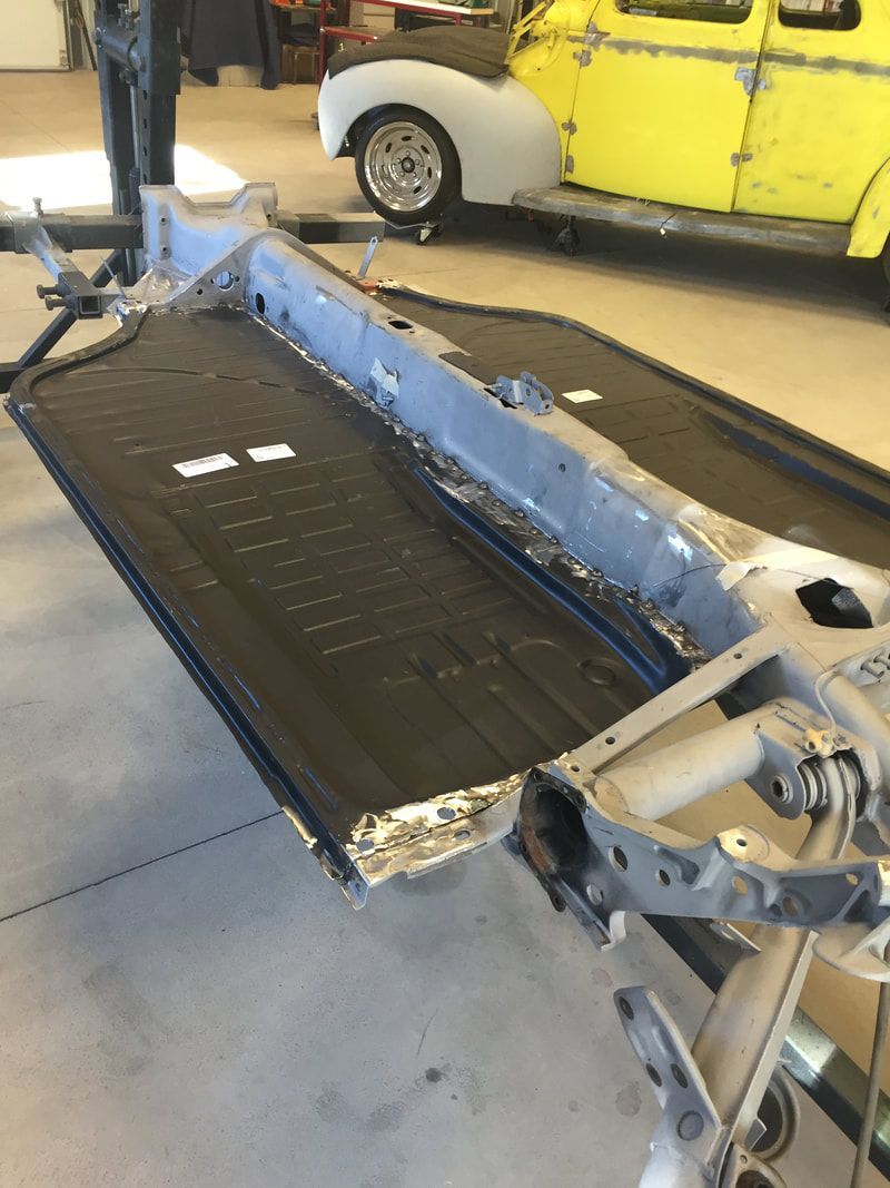 A yellow car is parked next to a blue car frame