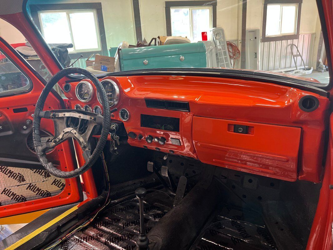 The interior of a red car is being restored in a garage.