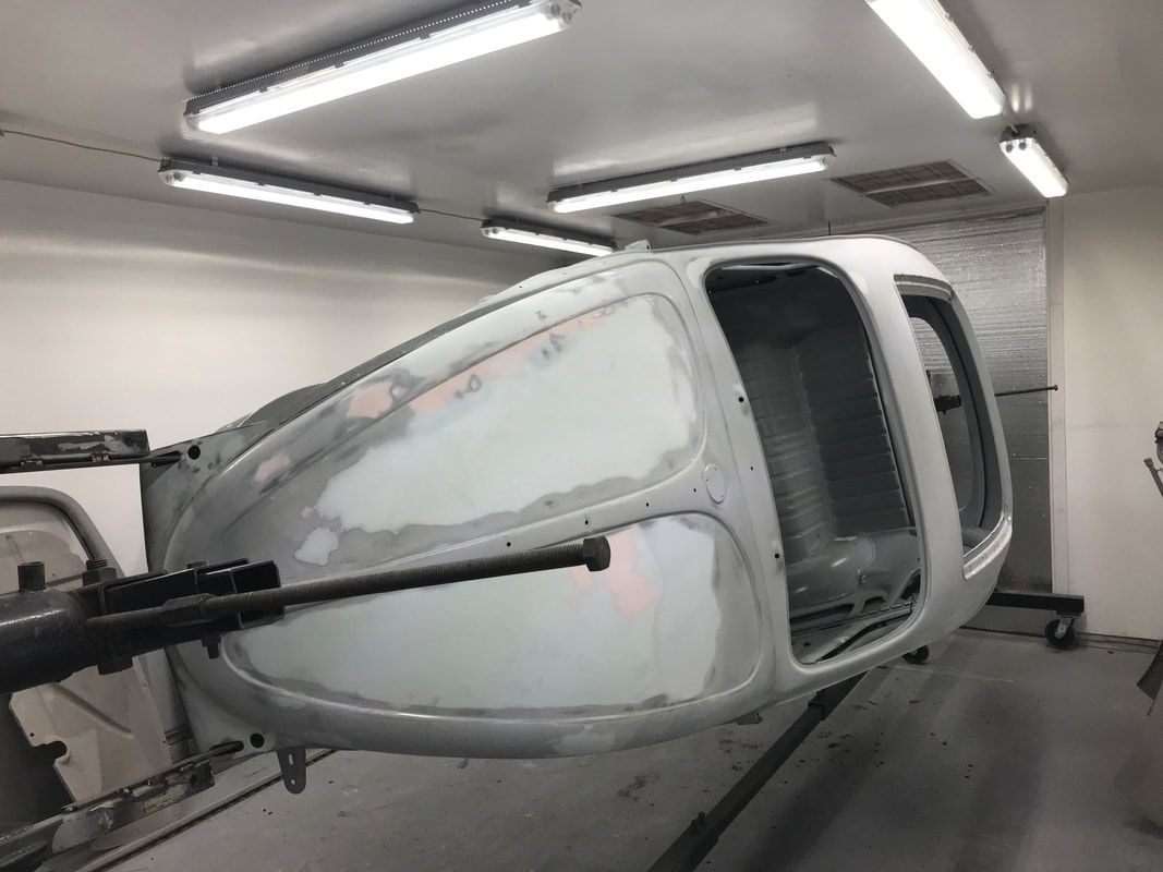 A white car is being painted in a garage.