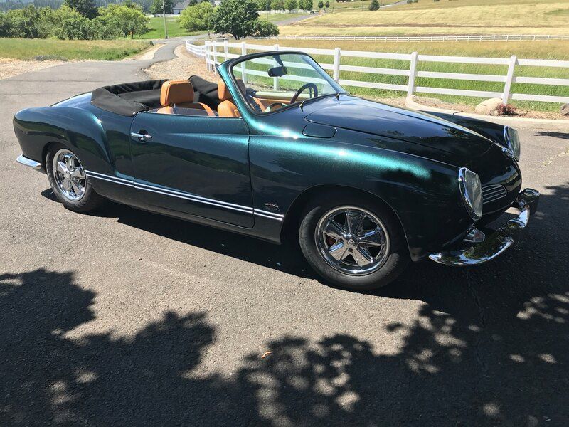 A green convertible car is parked on the side of the road.
