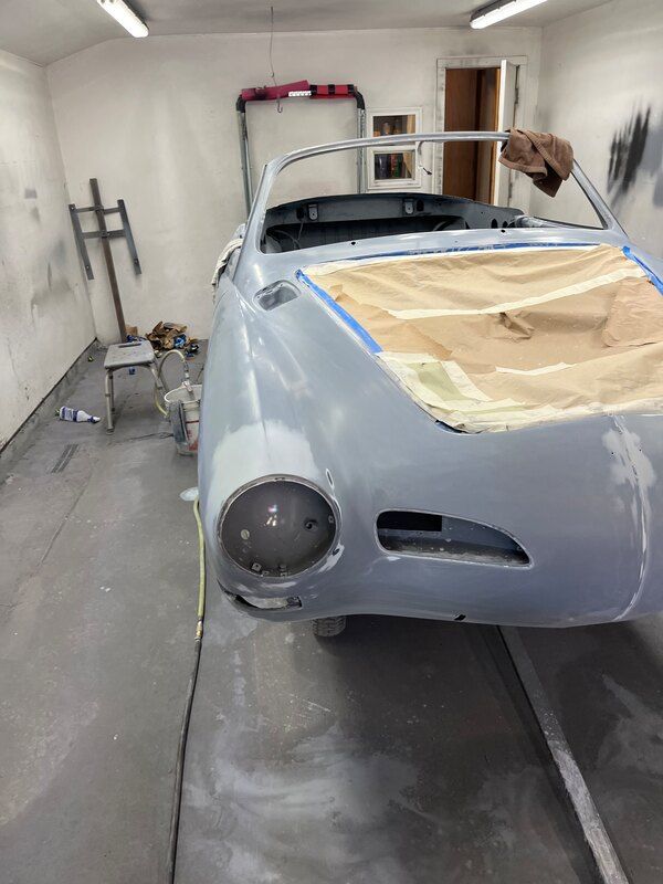 A car is being painted in a garage.