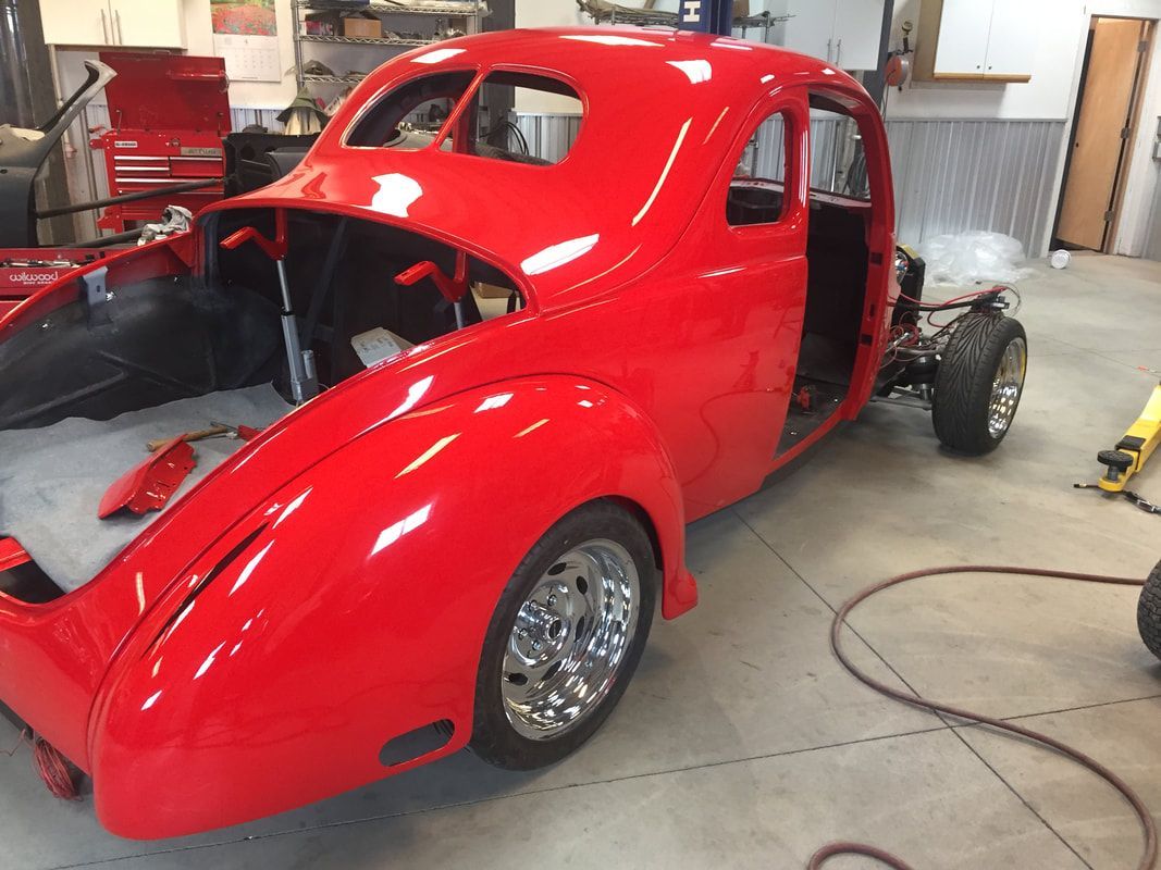 A red car is being restored in a garage.
