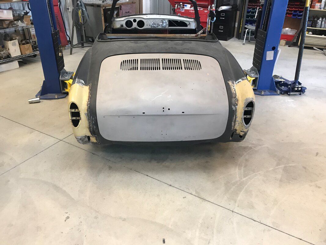 A car is sitting on a lift in a garage.