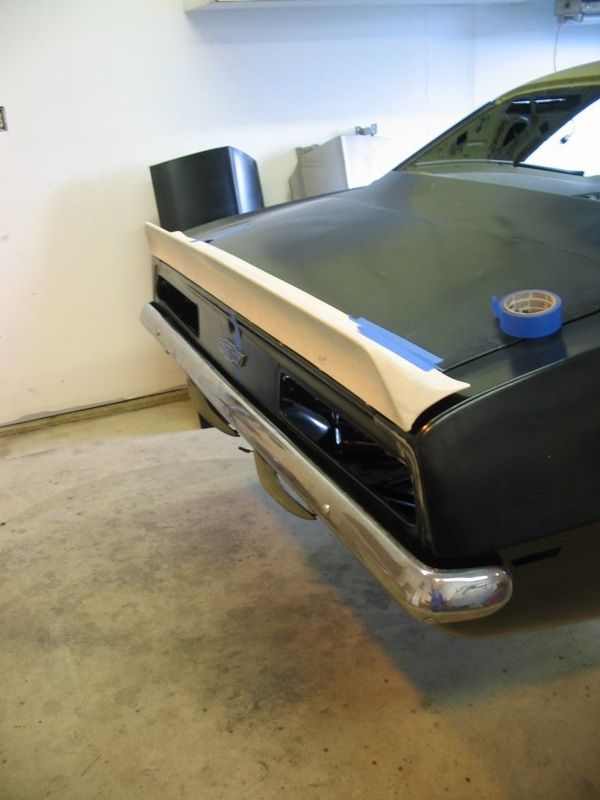 A black car is being painted in a garage