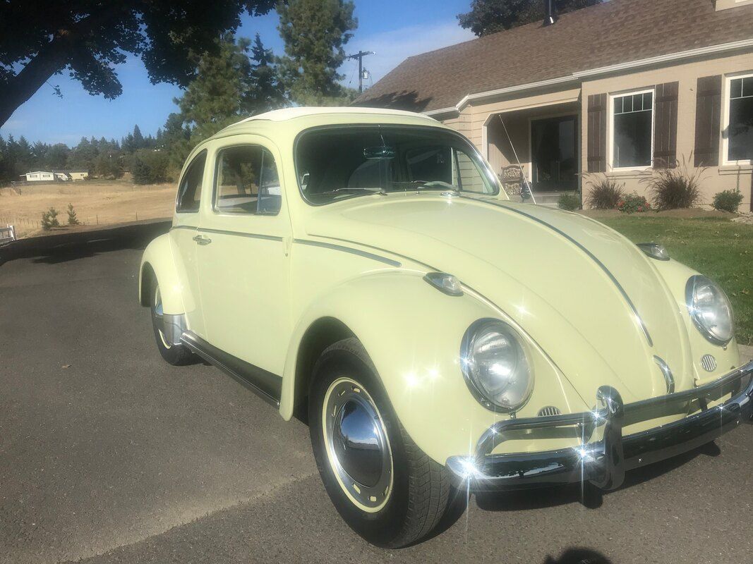 A yellow volkswagen beetle is parked in front of a house.