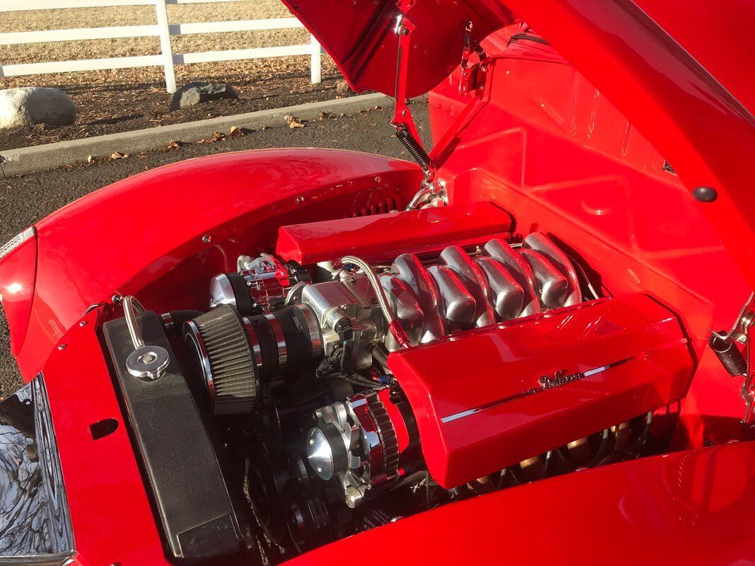 A red car with the hood up and the engine exposed