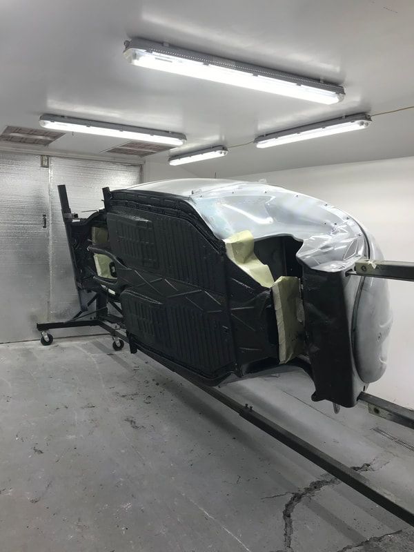 A car is being painted in a garage.