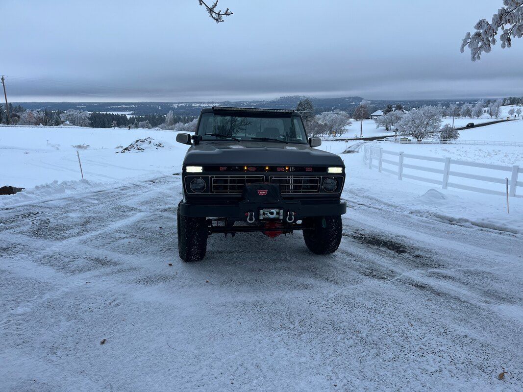 A truck is parked in the snow in a parking lot.
