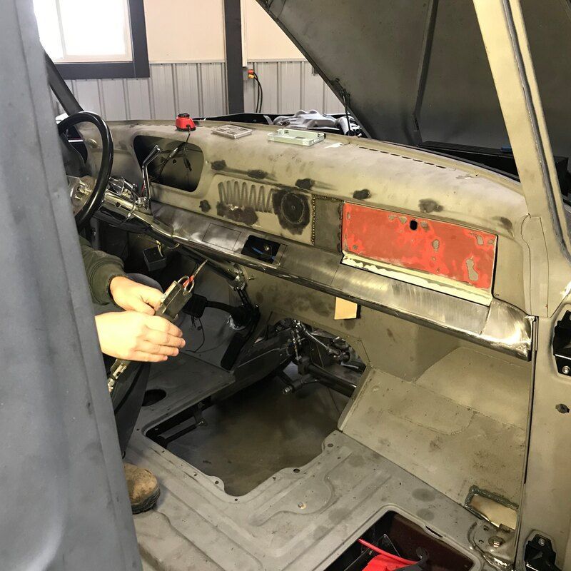 A person is working on a car with the hood open