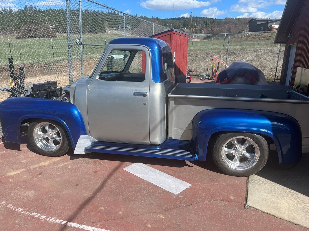 A blue and silver pickup truck is parked in a parking lot.