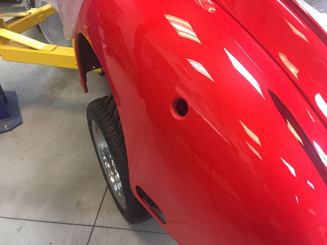 A red car is on a lift in a garage