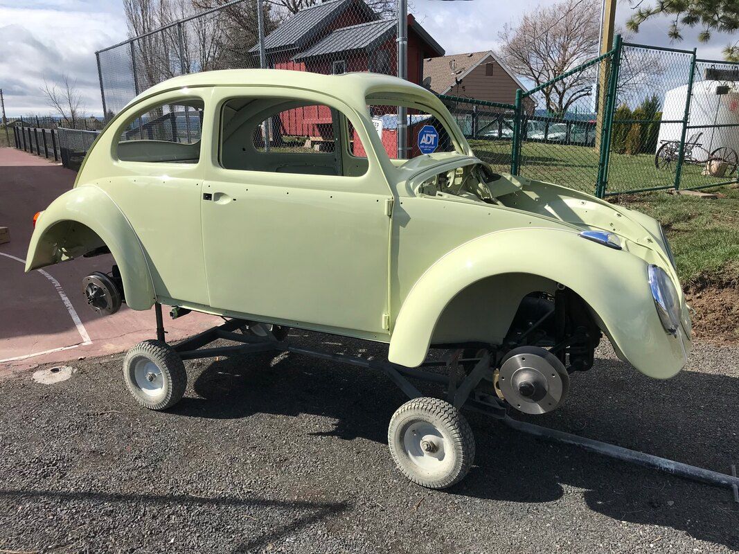 A yellow car is sitting on a trailer on the side of the road.