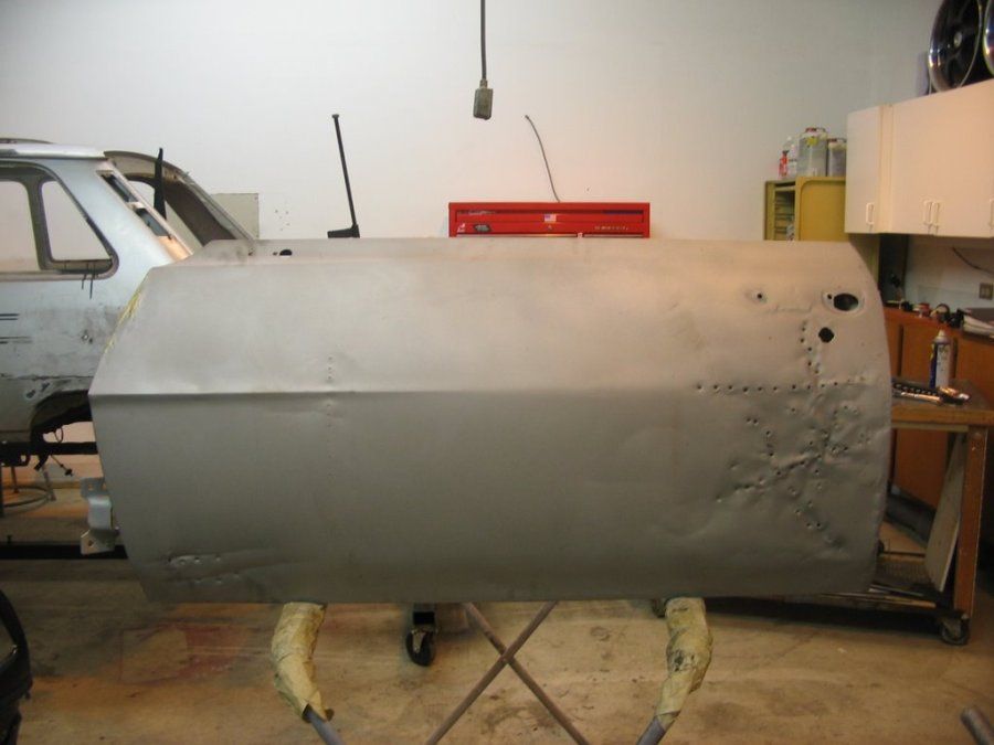 A car door is sitting on a stand in a garage