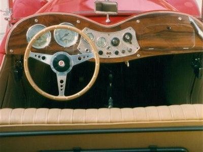 A red car with a wooden dashboard and steering wheel