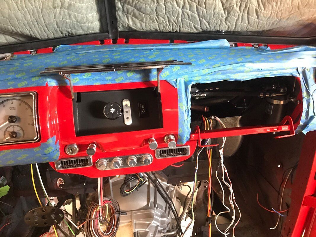 The dashboard of a red car is taped with blue tape.