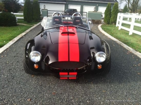 A black car with red stripes is parked in a driveway