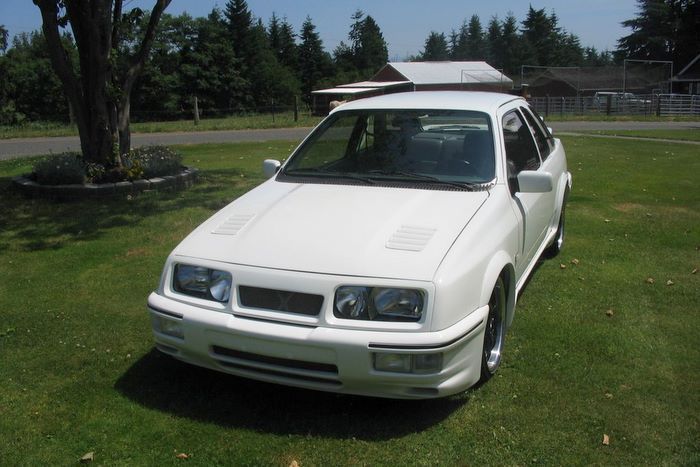 A white car is parked on a lush green field