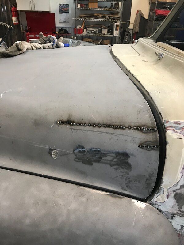 The hood of a car is being worked on in a garage.