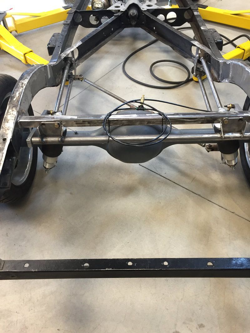 A car chassis is sitting on a concrete floor in a garage.