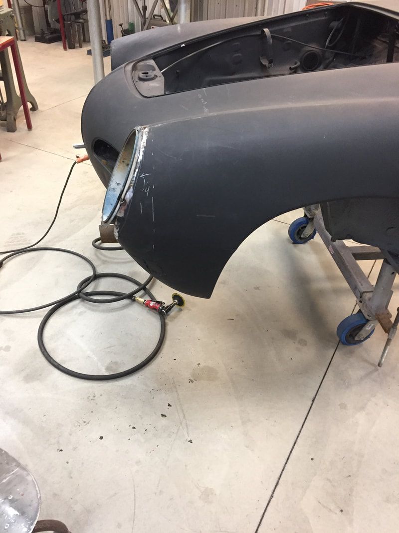 A black car is being worked on in a garage.