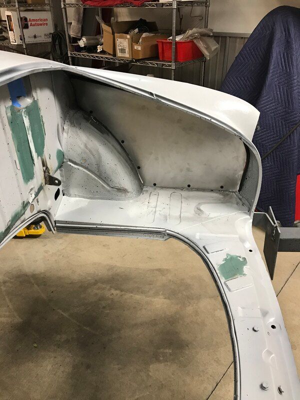 A white fender is sitting on the ground in a garage.