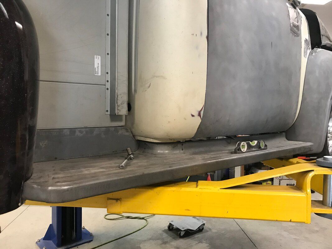 A car is sitting on a yellow lift in a garage.