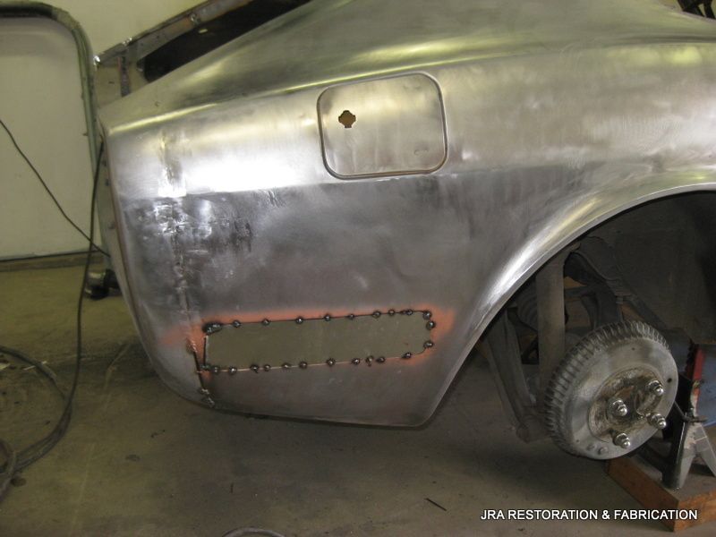 A silver car is being restored in a garage.