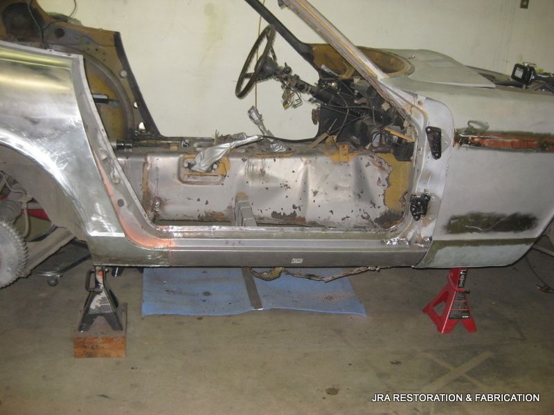 A silver car is being built in a garage